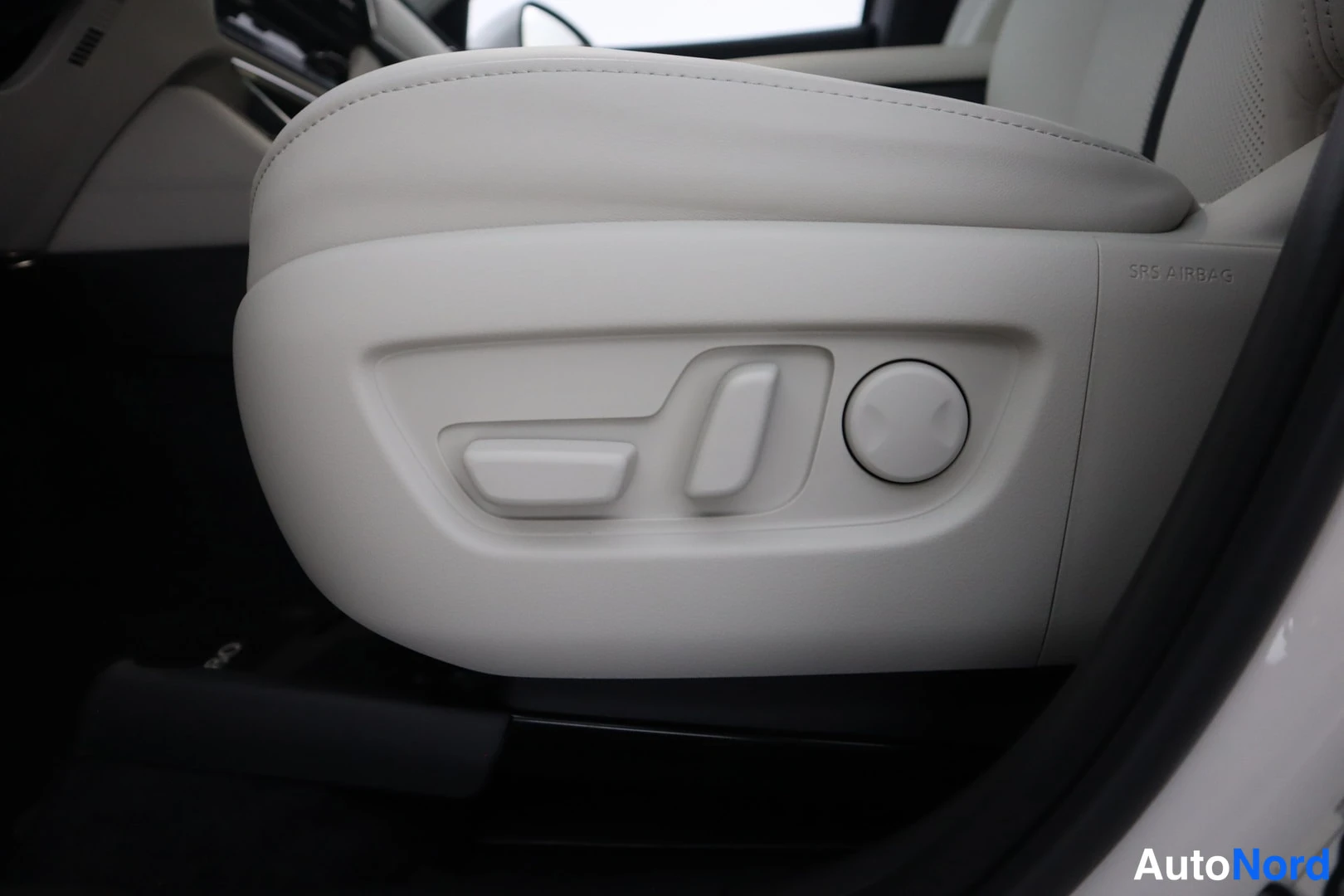 Muu: Vaanerenvärisen istuimen sivussa sähköistuimen säädönappulat ja pyöreä lannerannetuki; paneelissa teksti SRS AIRBAG.