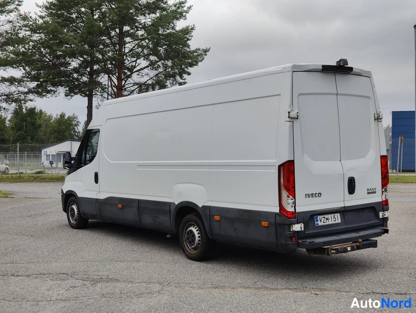 Takaviisto: Valkoinen Iveco Daily -pakettiauto kuvattuna takaa viistosti: takarovi IVECO-tekstillä, rekisterikilpi ja ajoneuvon vasen kylki näkyvät.