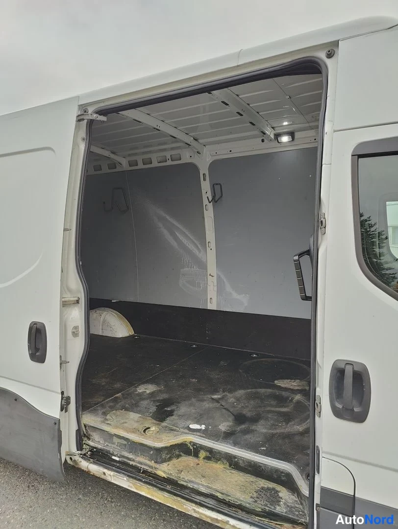 Sivulta: Side angle of open rear cargo door revealing grey interior paneling and floor with some stains and tie-down points
