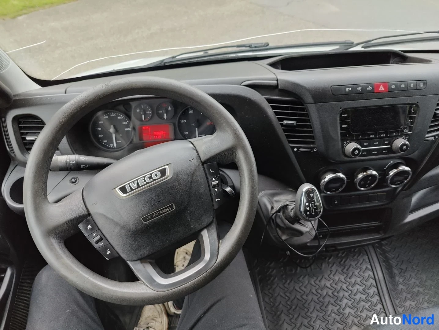 Ohjaamo: Ohjaamon sisäkuva: musta ohjauspyörä, jossa IVECO-logo ja painikkeet. Mittaristo, vaihdemahdolliisuusvalikolla varustettu vaihdekeppi sekä ilmanvaihtoaukot.