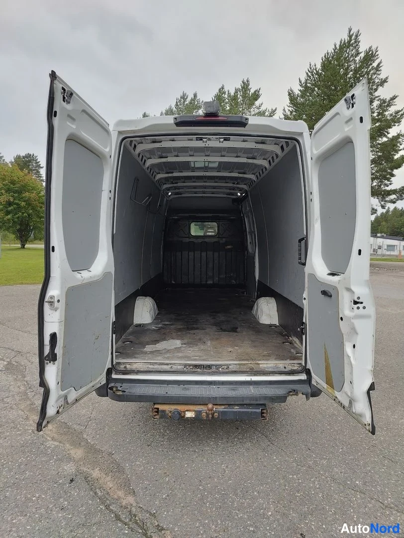Takaa: Back of a white van with rear doors wide open showing cargo space, tie down points on floor and metal partition at front bulkhead
