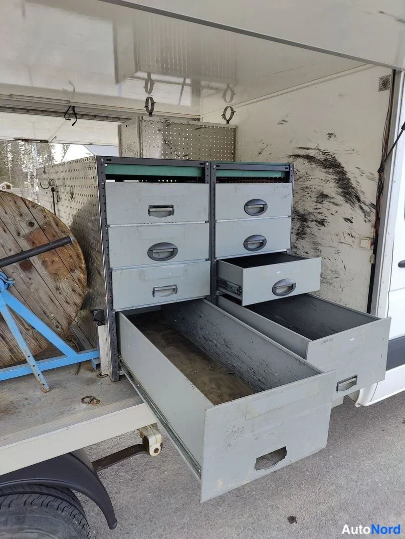 Takaviisto: Rear three-quarter view of the cargo area from the right side. Two grey filing cabinets with drawers are shown; several drawers are pulled open revealing empty