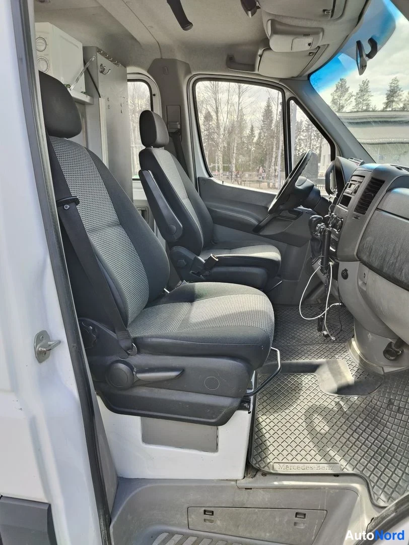 Etuistuimet: Ratti ja ohjaamon ovi näkyvät kuvassa. Ratin takana on ratakoneisto ja rattaan päällä on ohjauspaneeli. Ovesta tuleva valo palaa sisään.