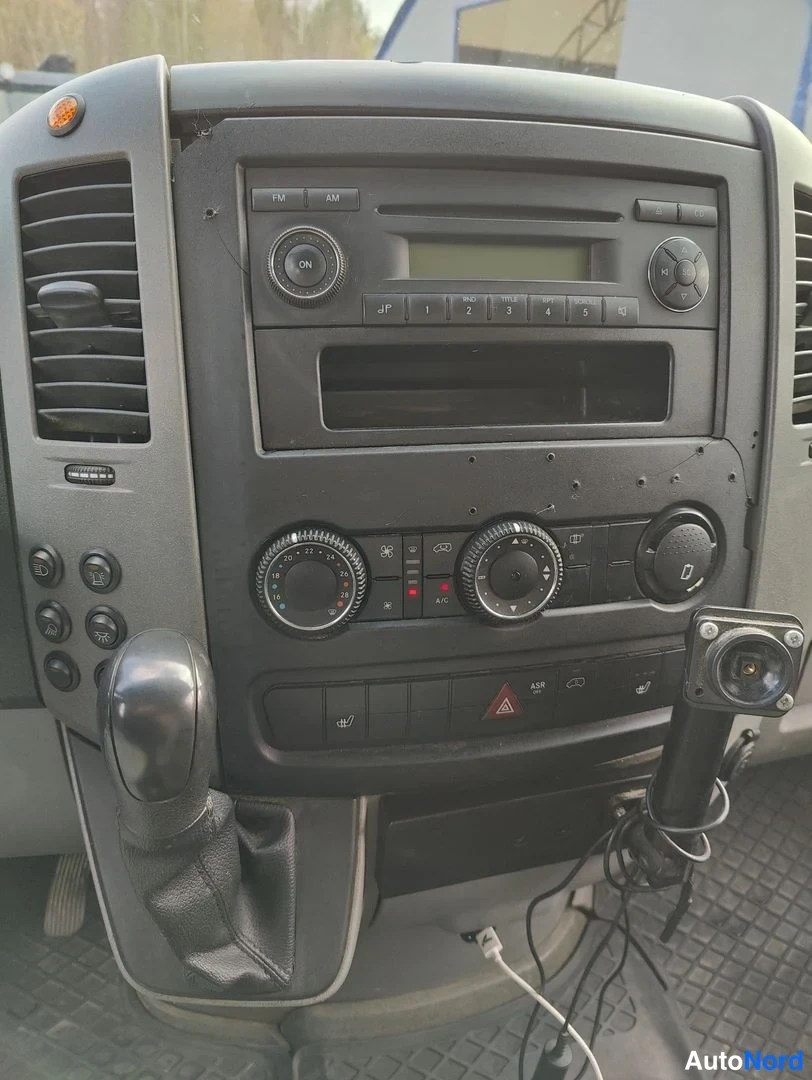 Yksityiskohta: Tarkka kuva keskustiehostosta ja radio-/ilmastointikytkimistä. Radioyksikkö ylhäällä, ilmastointipaineet alapuolella ja ohjainvaihtaja vasemmalla.