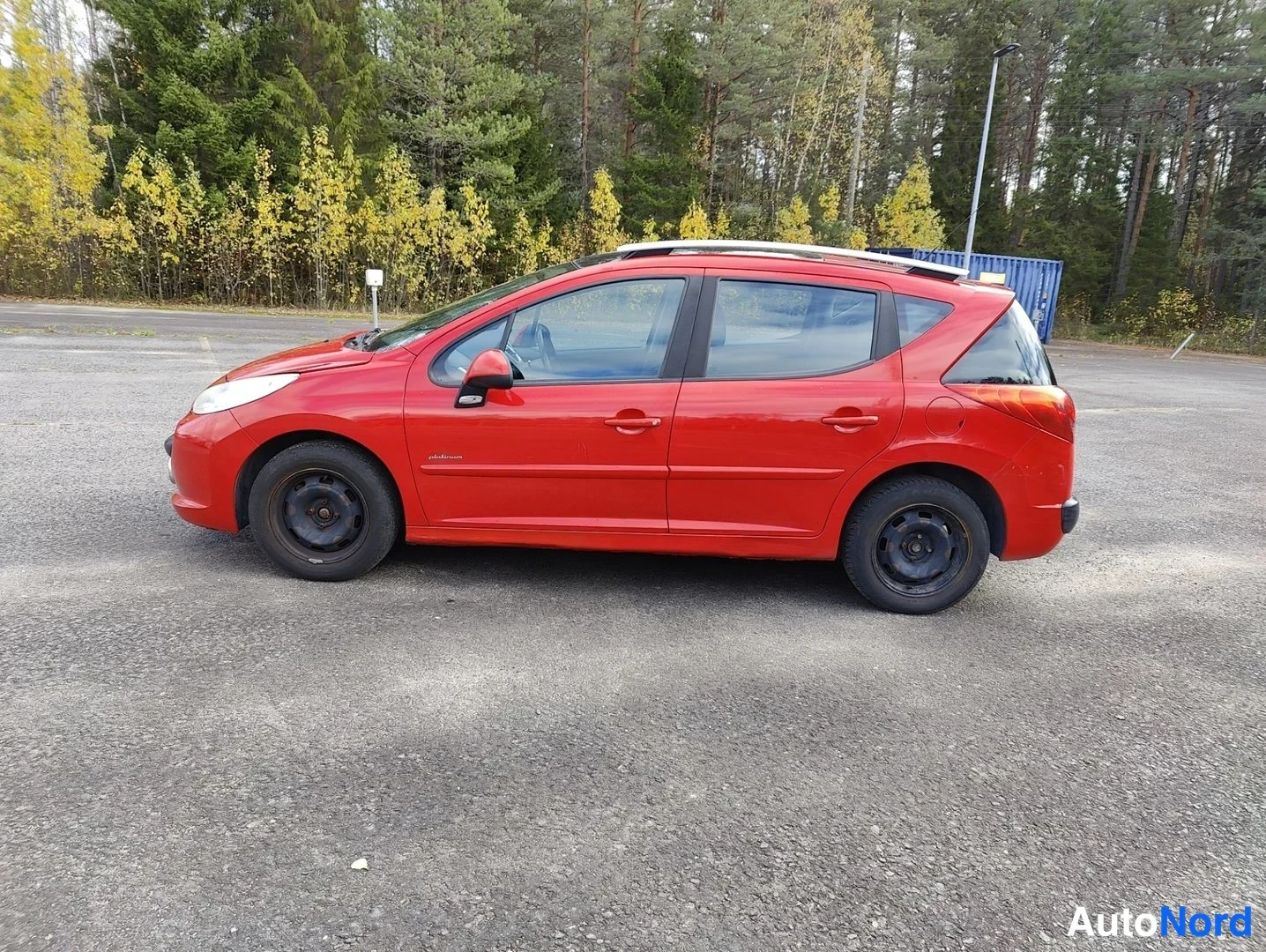 Sivulta: Side profile of a red hatchback showing four wheels, side mirrors, door handles, and roof rail tracks running along the upper edge.
