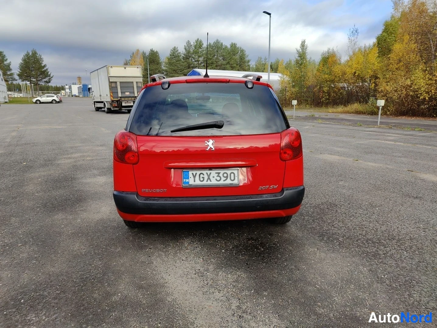 Takaa: Back view of a red hatchback with roof rails and black rear bumper.