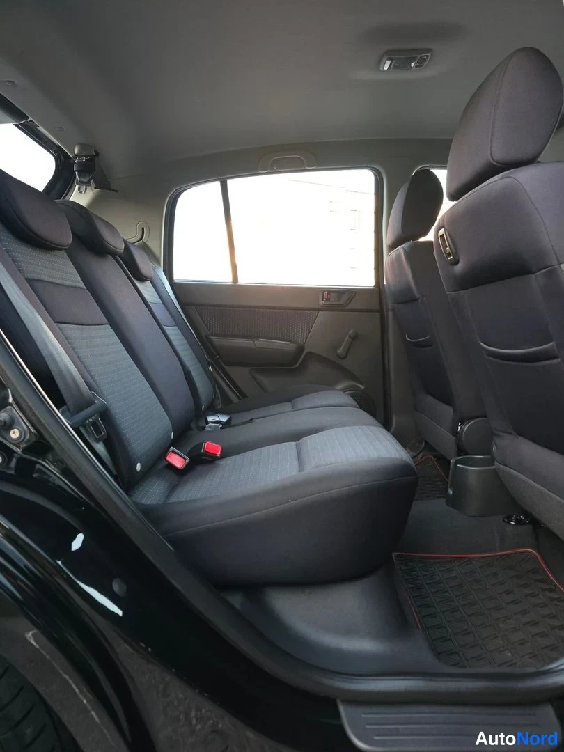 Takaistuimet: Rear passenger area showing a bench seat upholstered in two-tone dark fabric. Two child seats are installed using ISOFIX connectors. A floor mat is visible in t