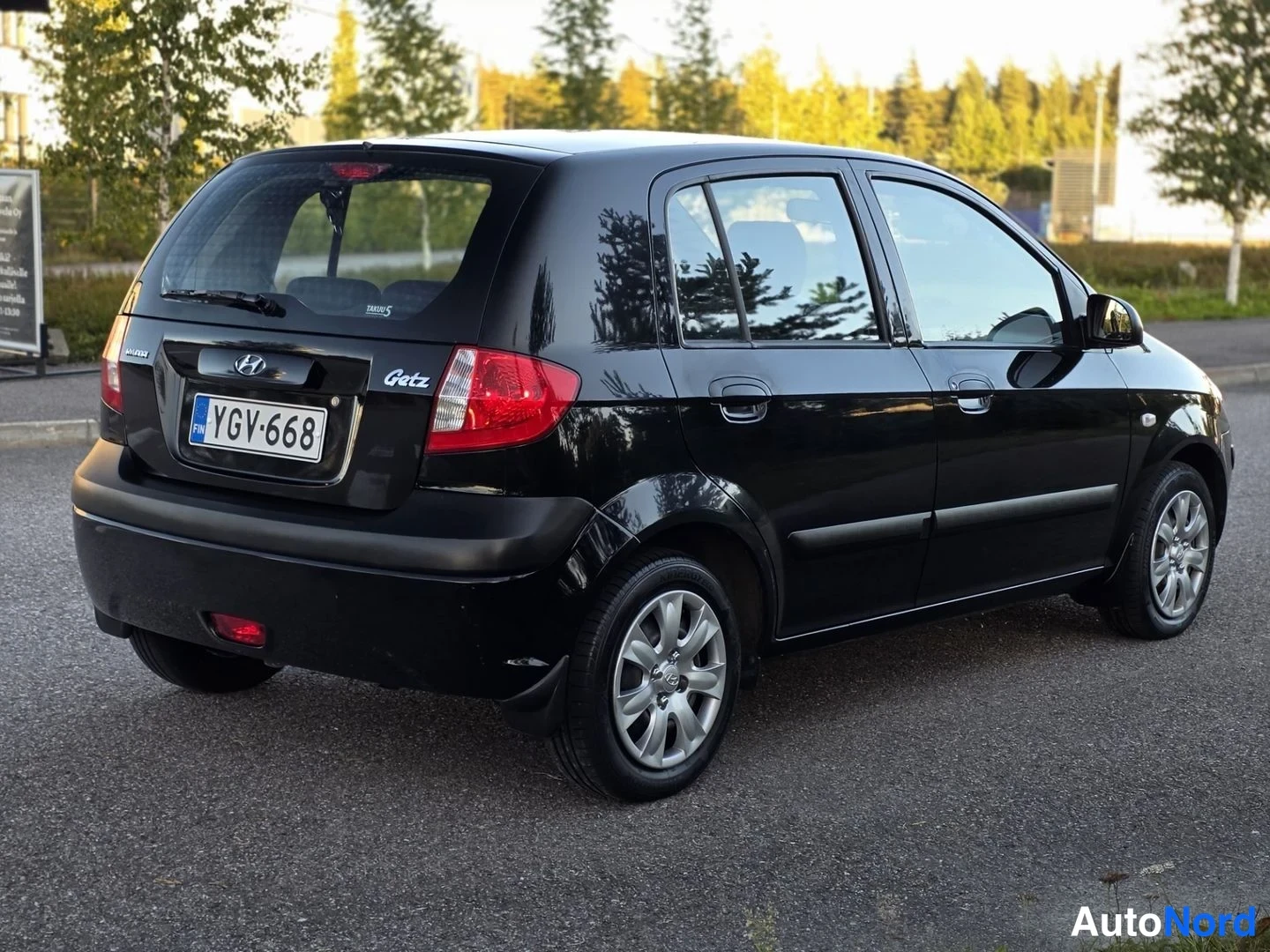 Takaviisto: Musta Hyundai Getz -automobiili, kuvaan näkyy auto takaa ja oikealta puolelta. Takana on rekisterikilpi ja sivupeilit mustat.