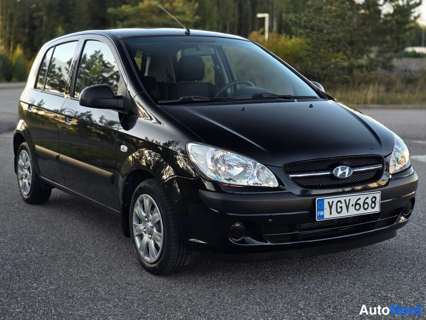 Etuviisto, nokka vasemmalle: Musta Hyundai Getz -auto kuvattuna etupuolelta ja vasemmalta puolelta. Etusuoja, etuvalot ja Hyundai-namelog ovat näkyvissä. Sivut peilikuvioissa.