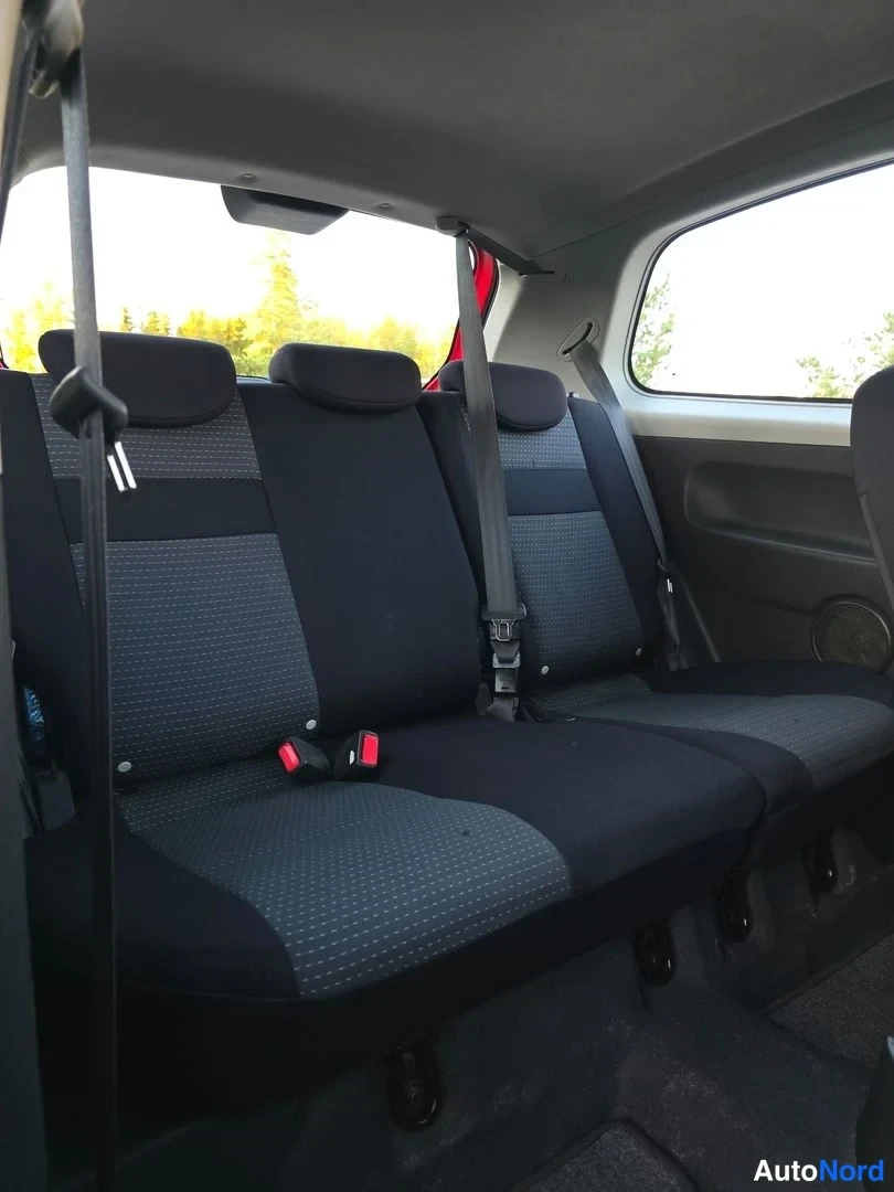 Takaistuimet: Interior shot showing dark fabric rear bench seat with three headrests and seatbelts.