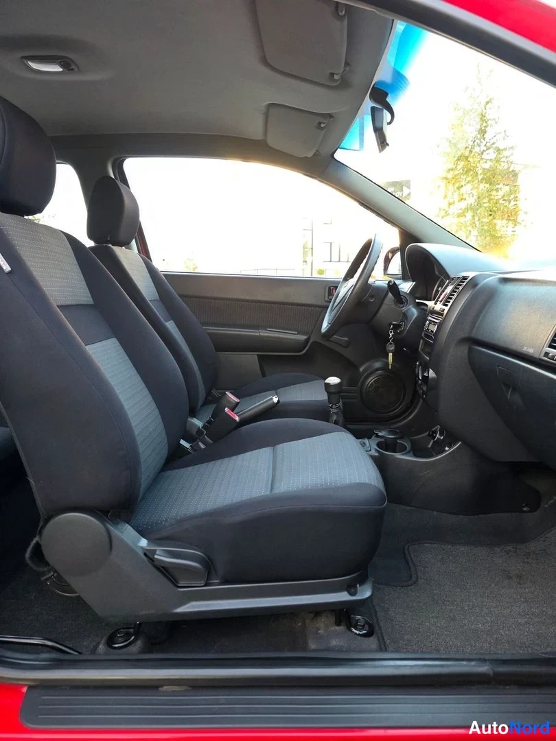 Etuistuimet: Front interior from the passenger door showing two front bucket seats, manual gear lever and steering wheel.