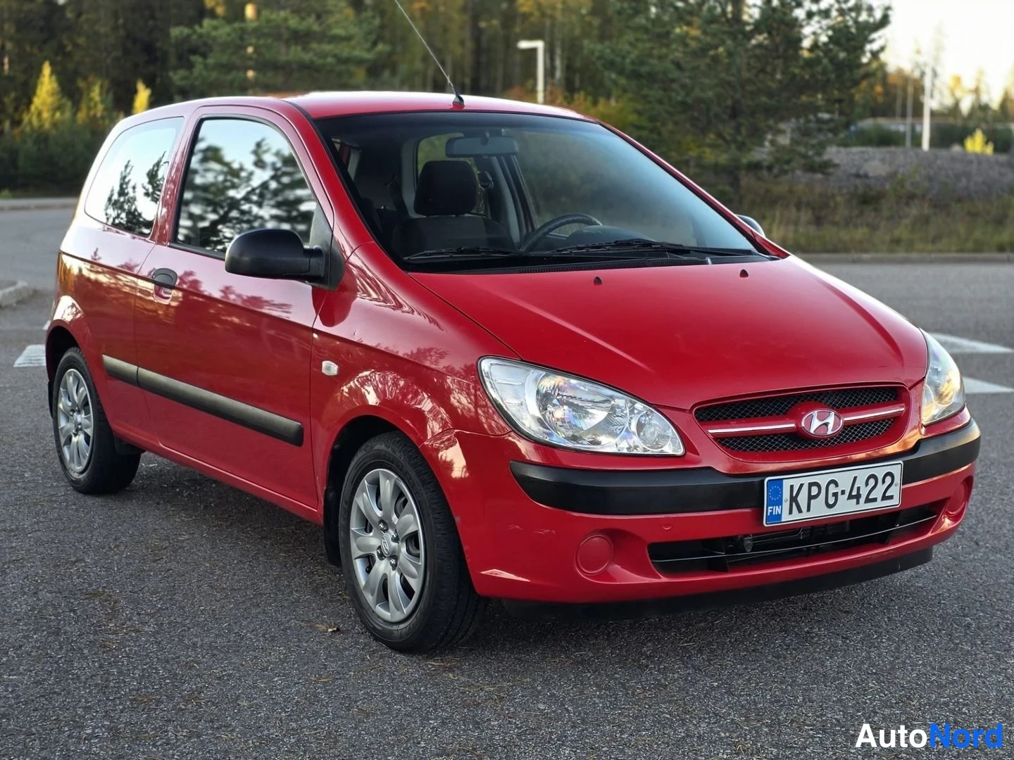 Etuviisto, nokka oikealle: Punainen Hyundai Getz kuvattuna edestä viistosti, keula oikealla; etusäleikössä Hyundai-merkki ja rekisterikilpi, musta puskurilista ja sivupeilien musta
