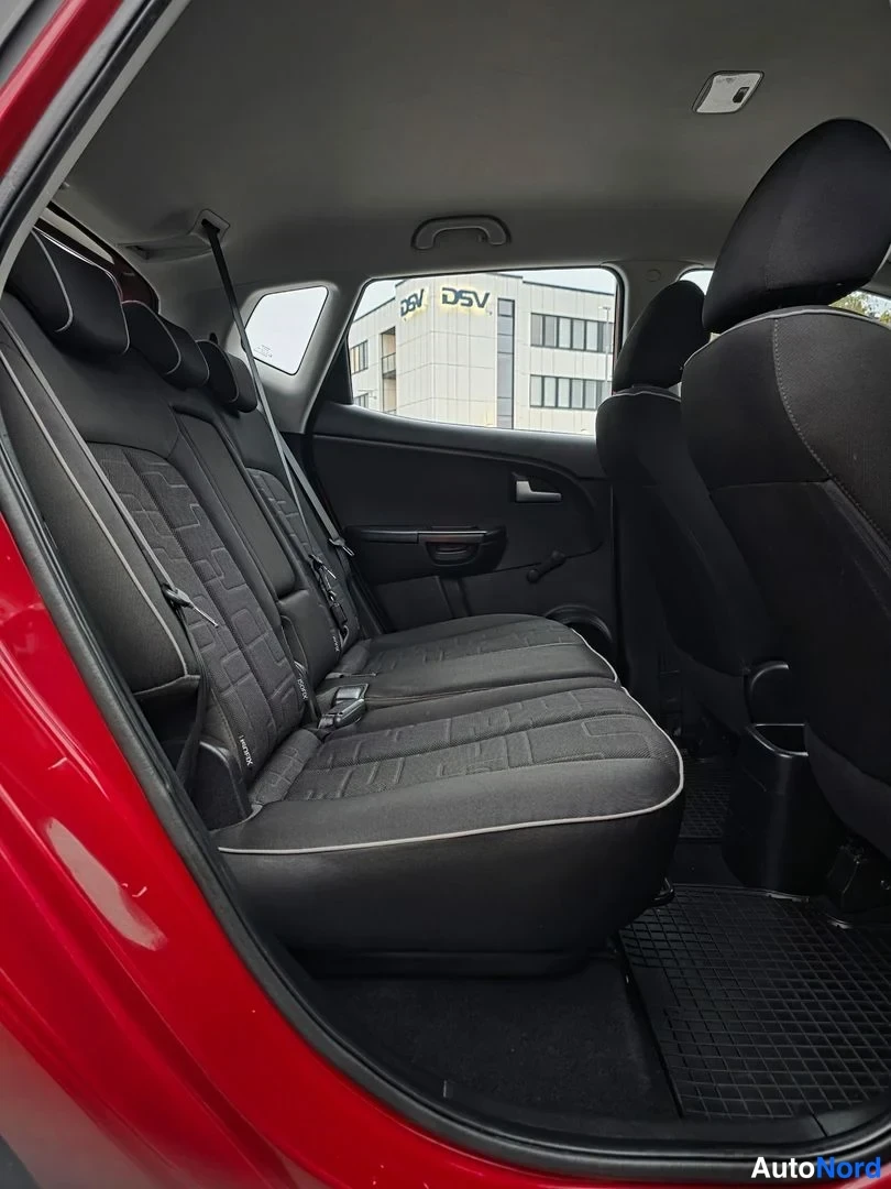 Takaistuimet: Interior view of three black fabric rear seats. Black carpeted floor and door panel to the right.