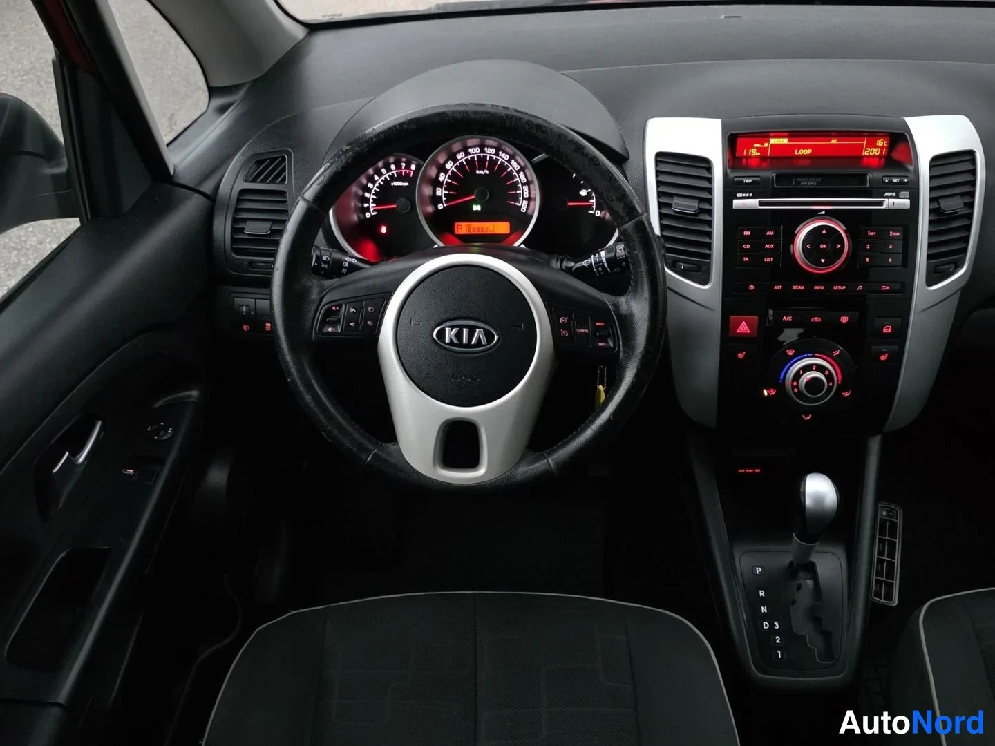 Muu: Interior shot from the driver's side showing the steering wheel, illuminated instrument cluster with a 'P' indicator for park, and center stack with climate con