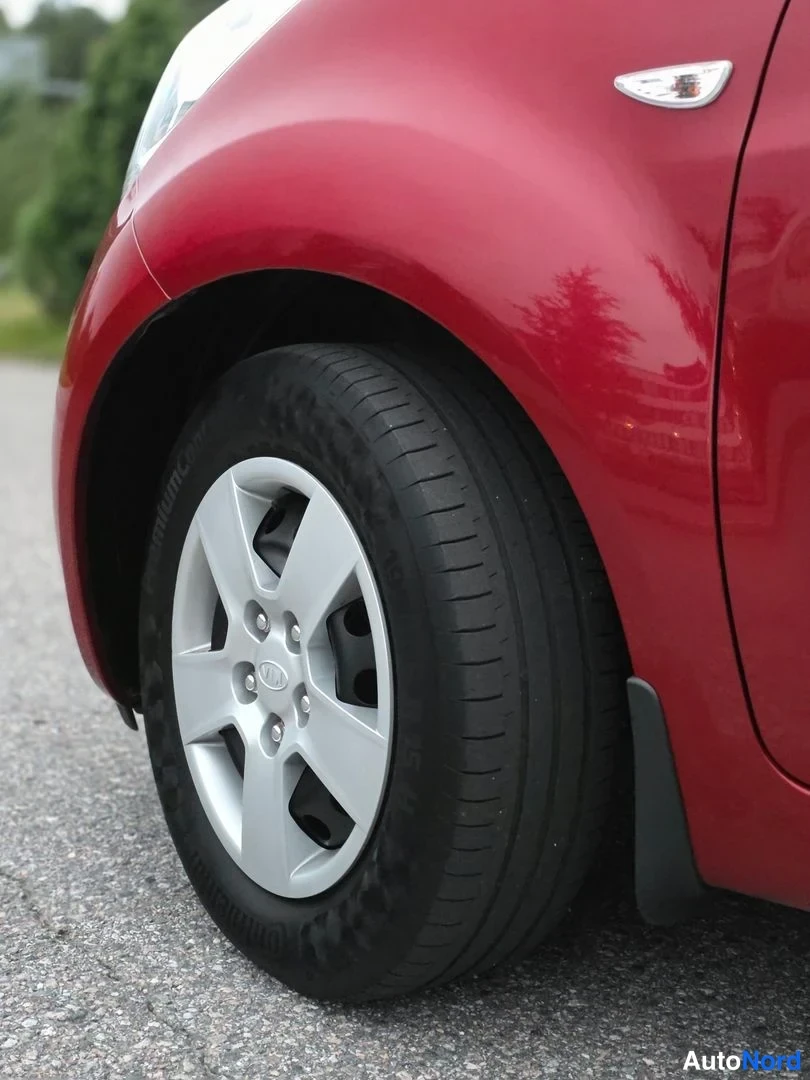 Yksityiskohta: Close-up of a silver five-spoke alloy wheel with red car bodywork above and below.