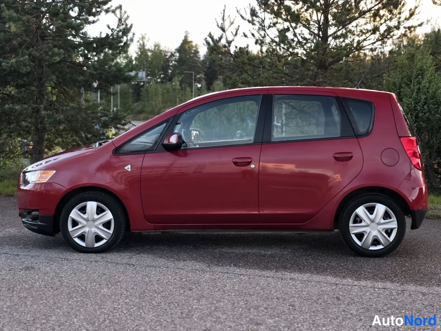 Sivulta: Punaisen Mitsubishin kylki on kokonaan näkyvissä, ovet ja renkaat selkeästi havaittavissa.