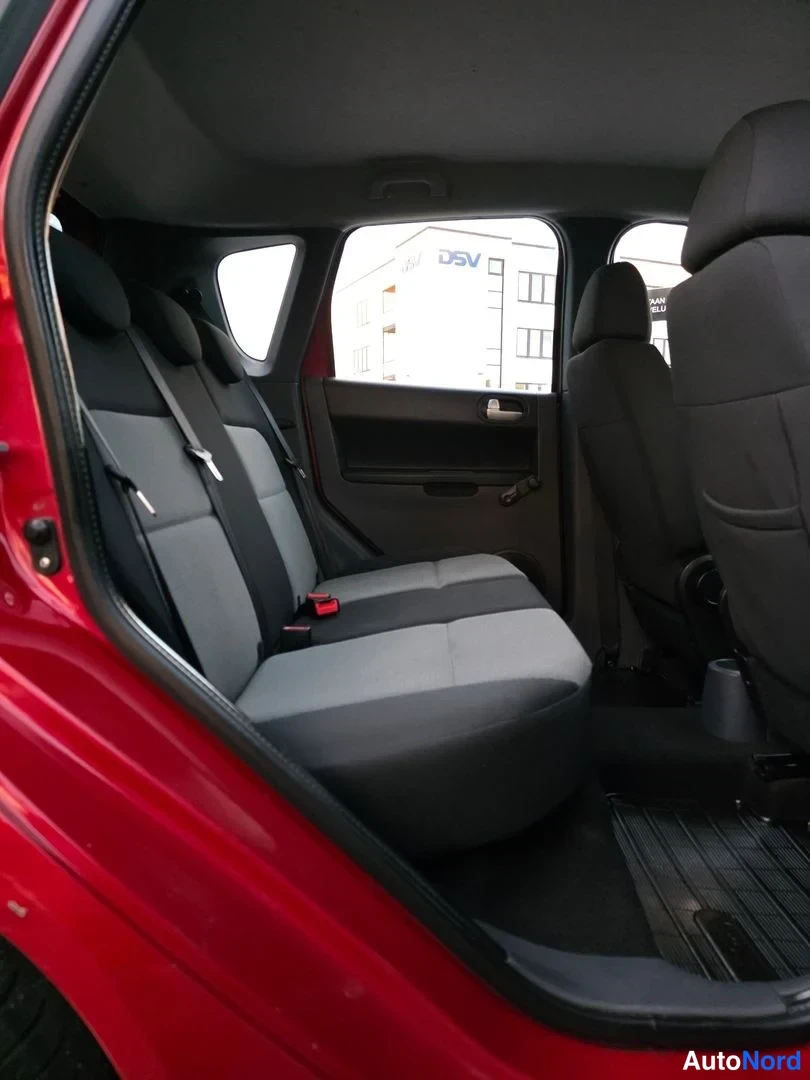 Takaistuimet: Interior view from the open rear door showing grey fabric rear bench seat and black door panel