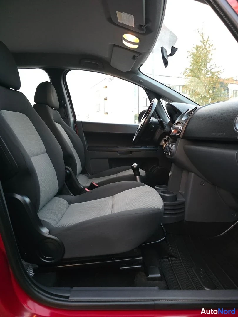 Etuistuimet: Interior view of the front passenger area showing a grey fabric seat headrest steering wheel dashboard cup holders and gear lever