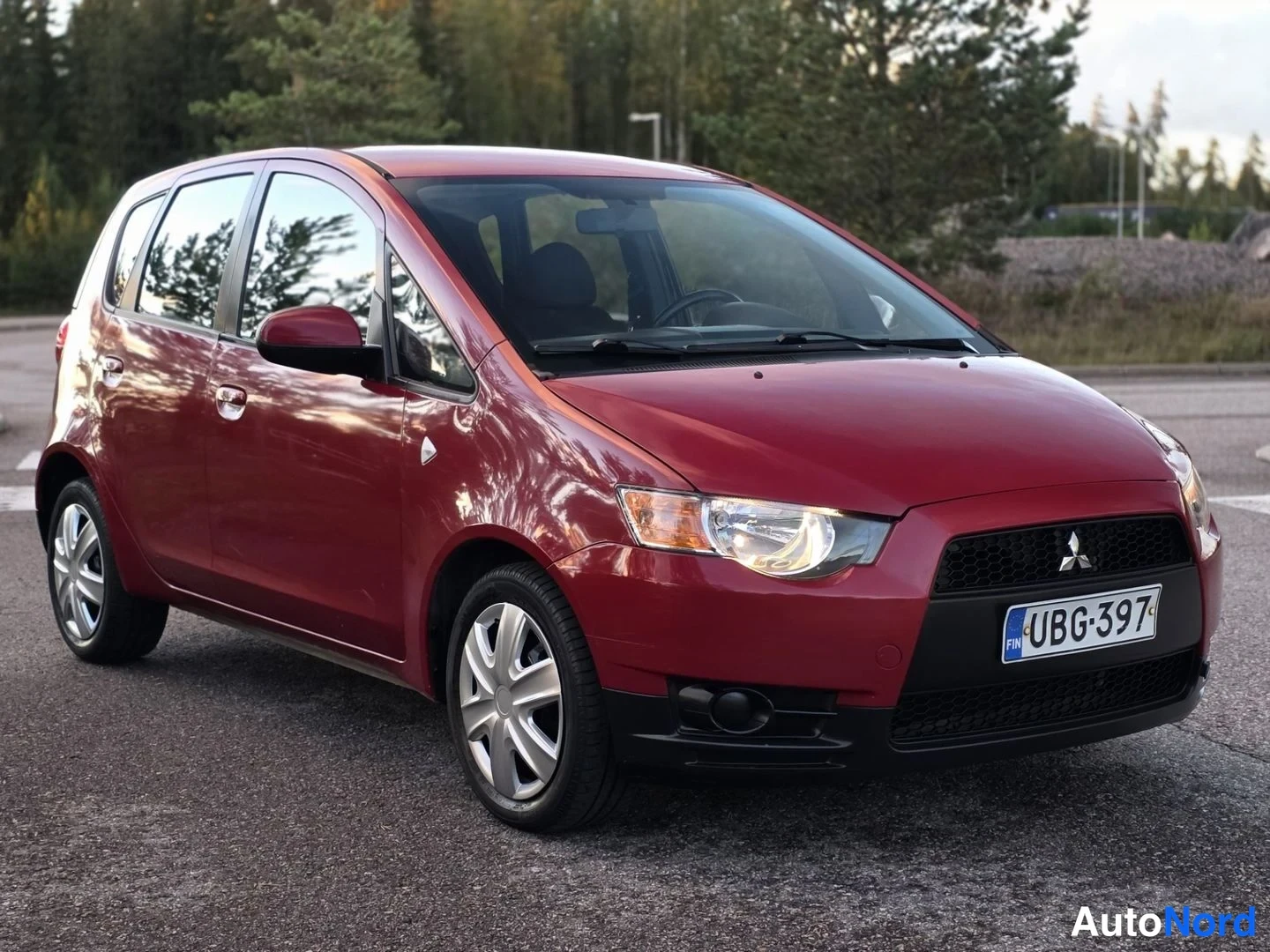 Etuviisto, nokka oikealle: Mitsubishi Colt -etukulma oikealta. Punainen auto etu- ja sivunäkymällä.