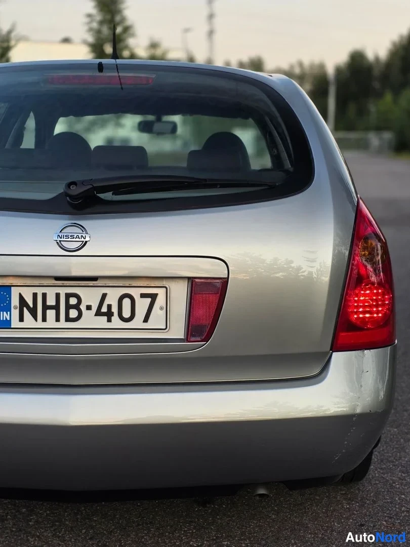 Takaa: Takapuoli näytetään hopeisella Nissan- hatchbackilla. Takavalot, takakontin luukku ja NISSAN-merkki on näkyvissä. Myös Finnish rekisterikilpi '' ja takaikkunan
