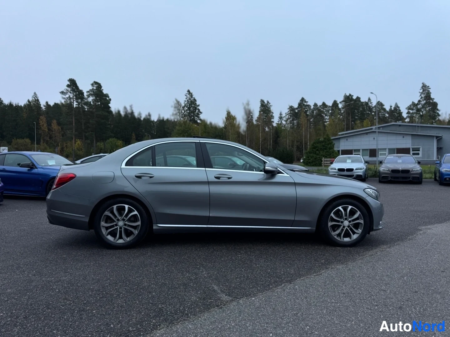 Sivulta: Oikea kokosivunäkymä harmaasta Mercedes-Benz C-sarjan sedanista. Kevytmetallivanteet, ovien kahvat ja ikkunoiden kehät ovat näkyvissä.