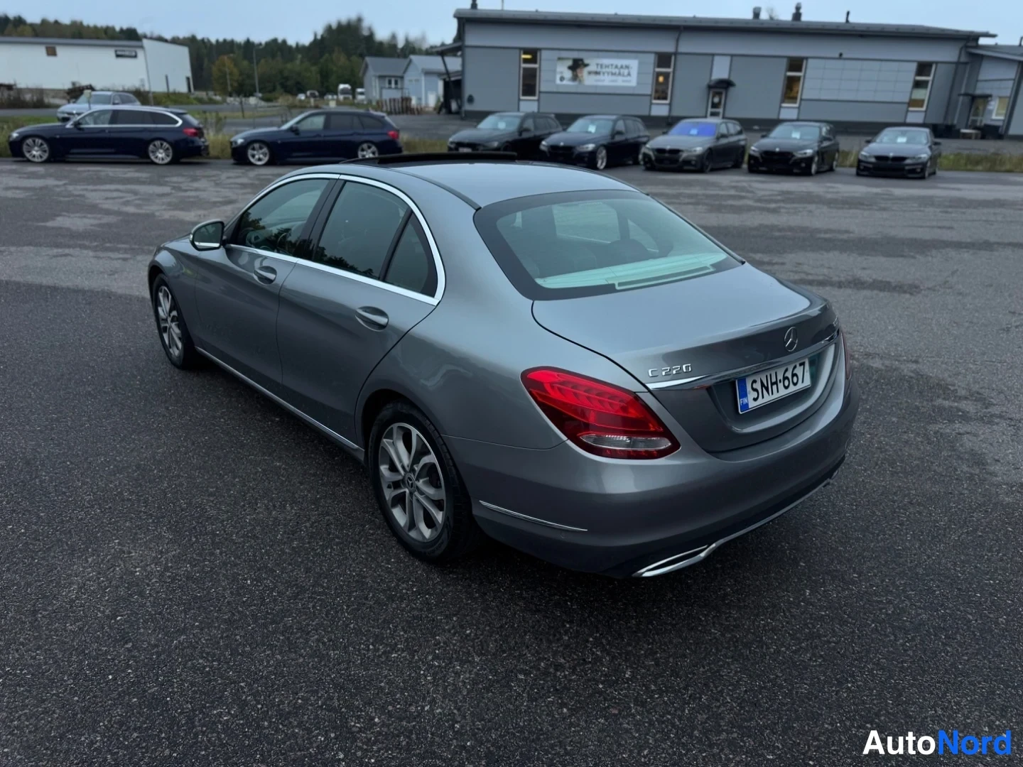 Takaviisto: Takakulmasta kuvattu harmaanharmaa Mercedes-Benz-sedan; peräluukun C 220 -merkintä, takavalot ja kylki näkyvissä, rekisteritunnus.