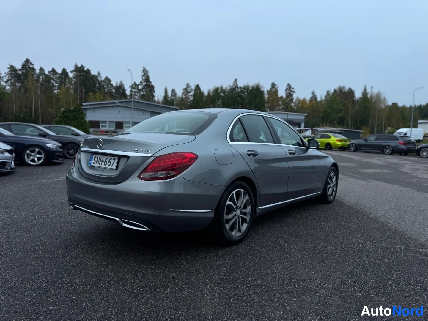 Takaviisto: Takaa ja oikeasta sivusta otettu kuva harmaaksi maalatussa Mercedes-Benz C-sarjan sedanissa. Takavalo, rekisterikilpi, kromipaneeli ja kevytmetallivanteet näkyv