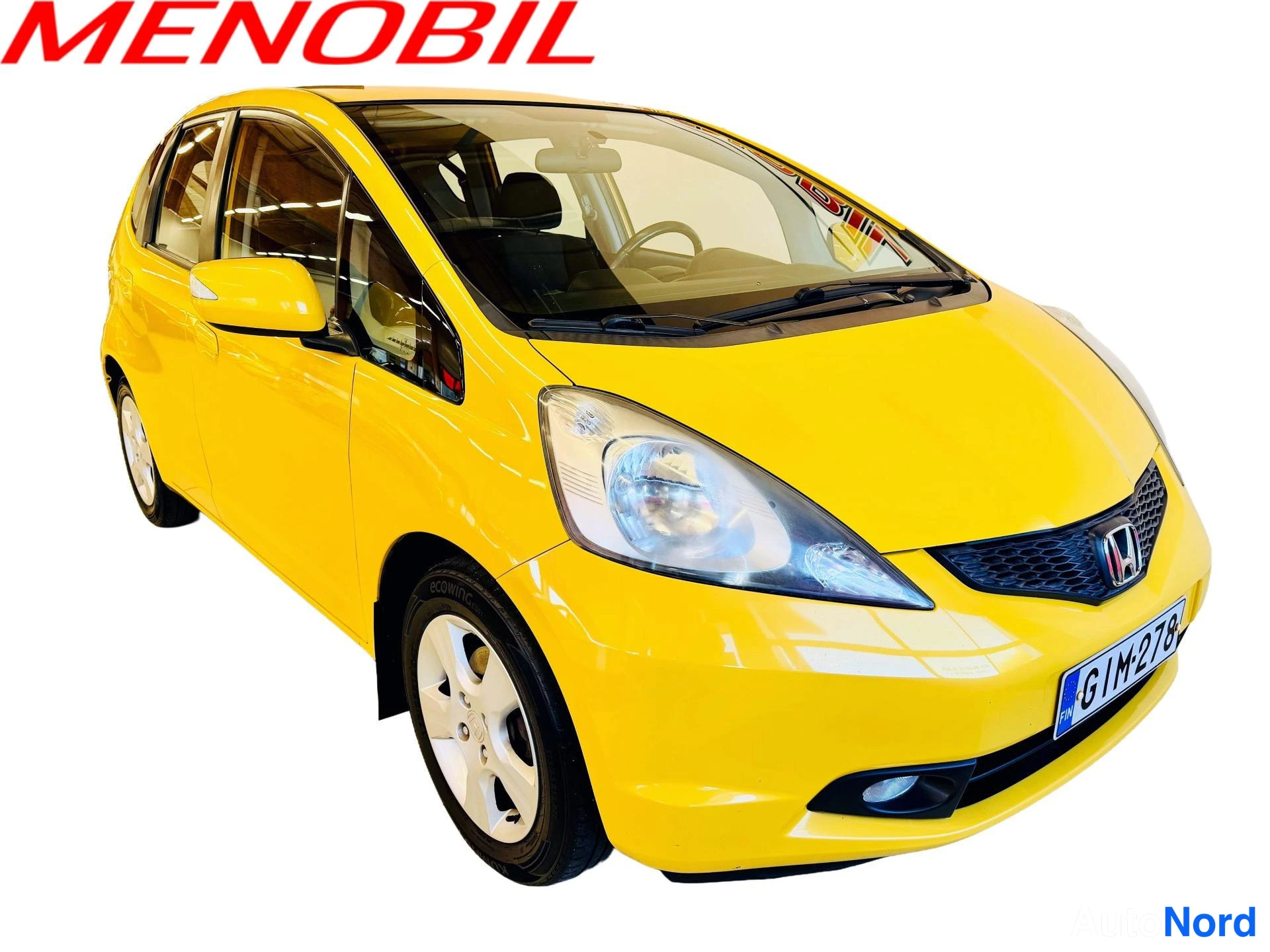 Etuviisto, nokka oikealle: Keltainen viistosti edestä oikealta kuvattu viisiovinen Honda, etusäleikkö ja etumoitti näkyvät oikealla, rekisterikilpi.