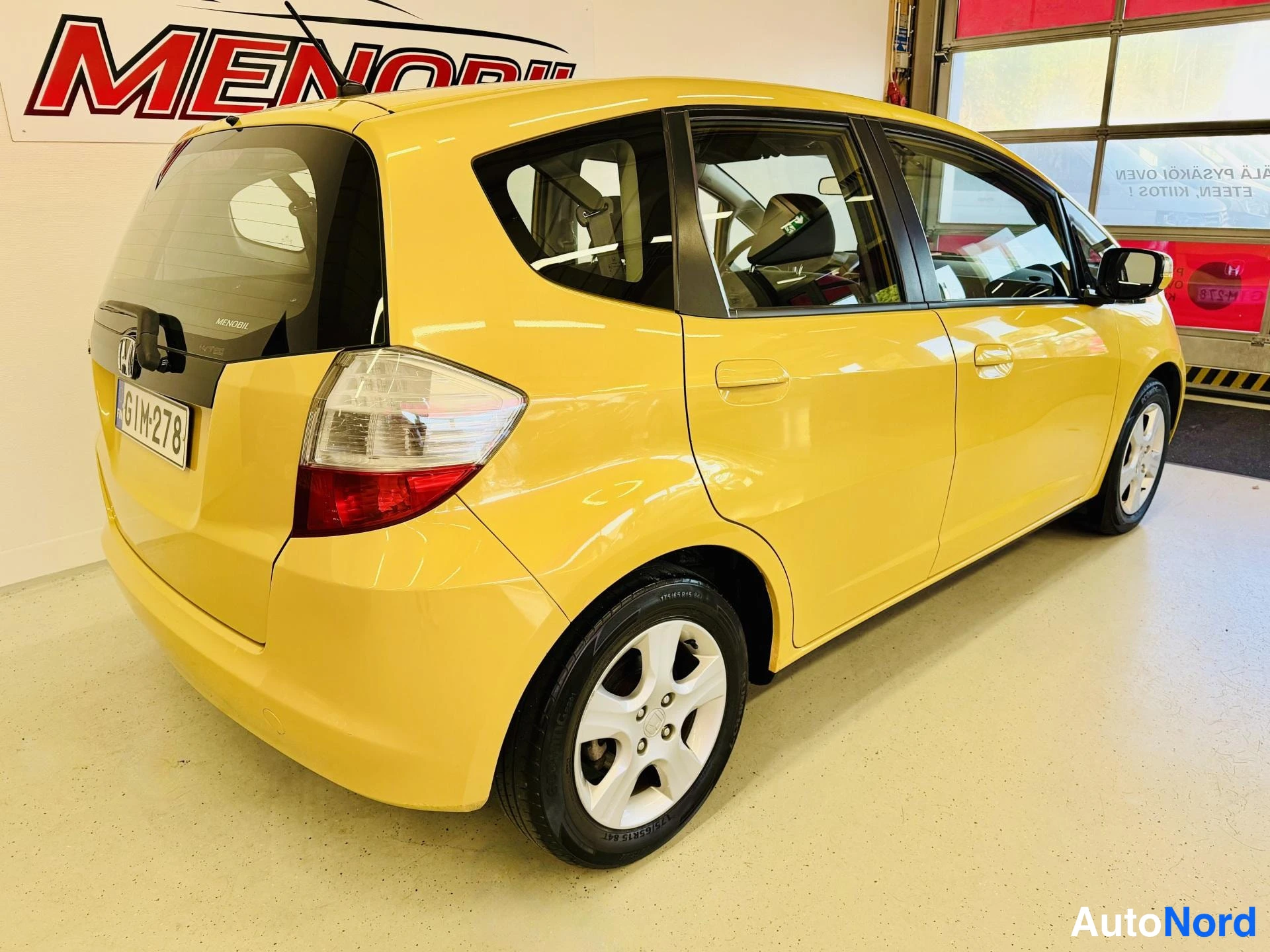 Takaviisto: Keltainen Honda Jazz takaviistolta, rekisterikilpi.
