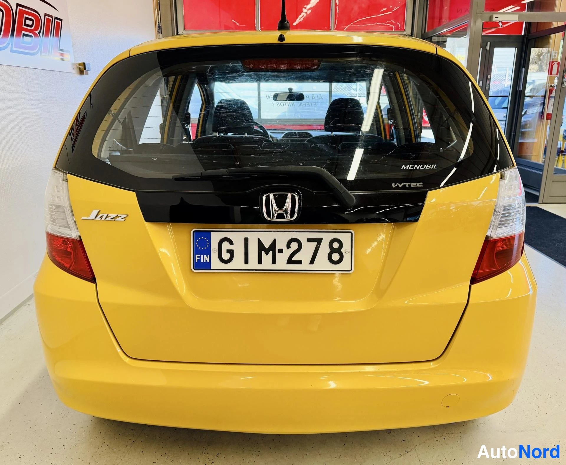 Takaa: Keltainen Honda Jazz suoraan takaa, rekisterikilpi.