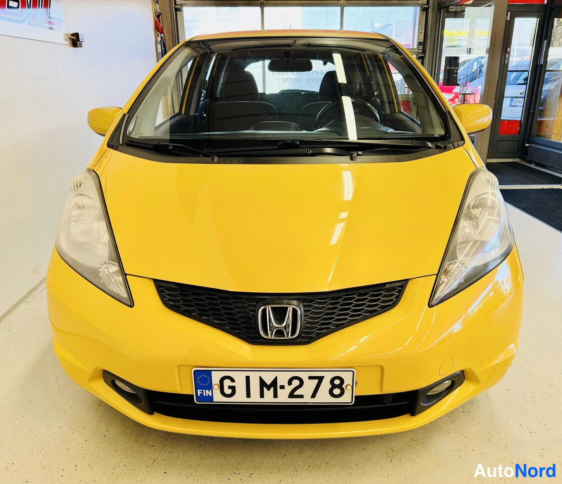 Edestä: Keltainen Honda Jazz suoraan edestä, rekisterikilpi.