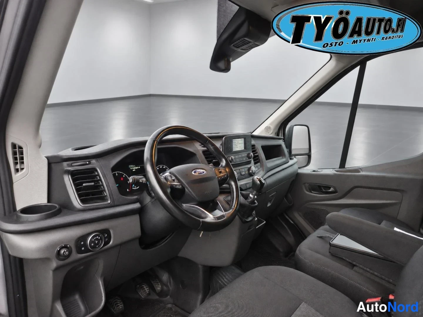 Ohjaamo: View of the driver's side interior showing the steering wheel, dashboard, gear stick and passenger seat.