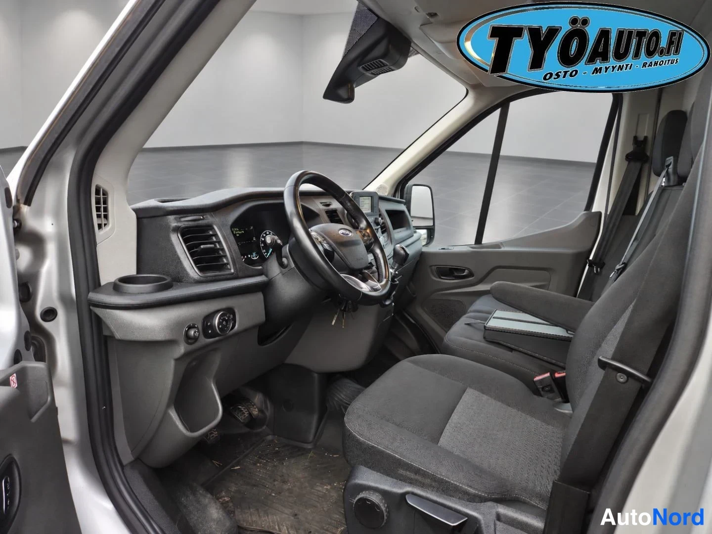 Etuistuimet: Wide view of the front cabin interior from the open driver's door, showing two front seats.
