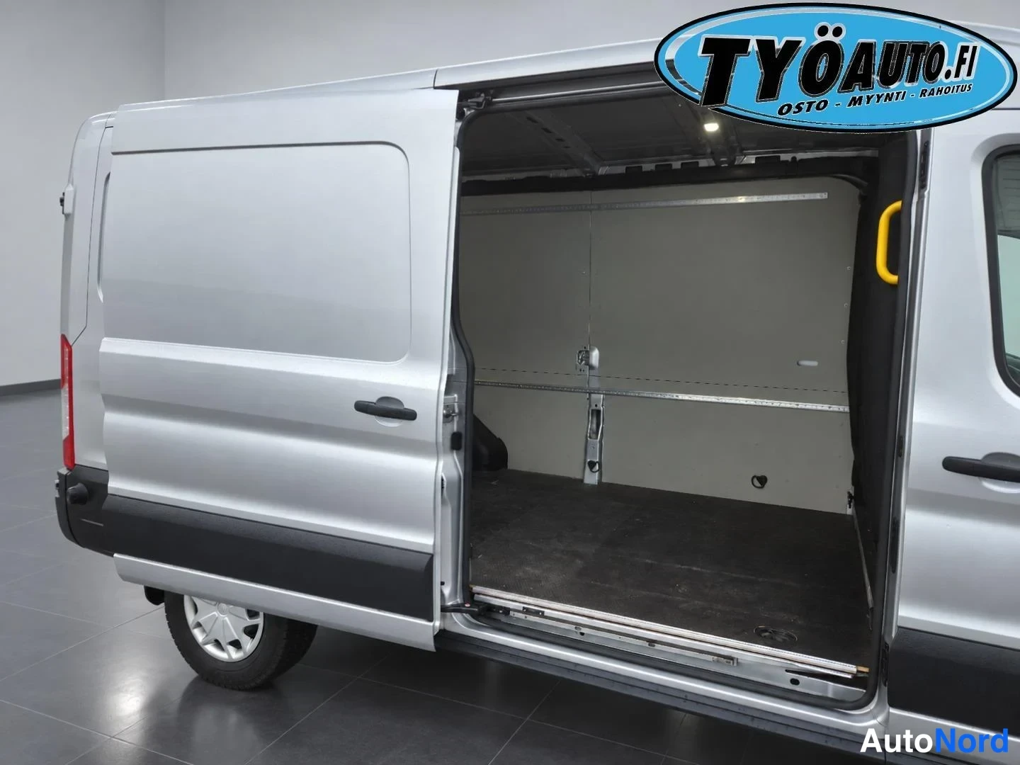 Takaviisto: Silver van cargo area viewed from left rear three-quarter with right sliding door open showing interior wall paneling and floor.