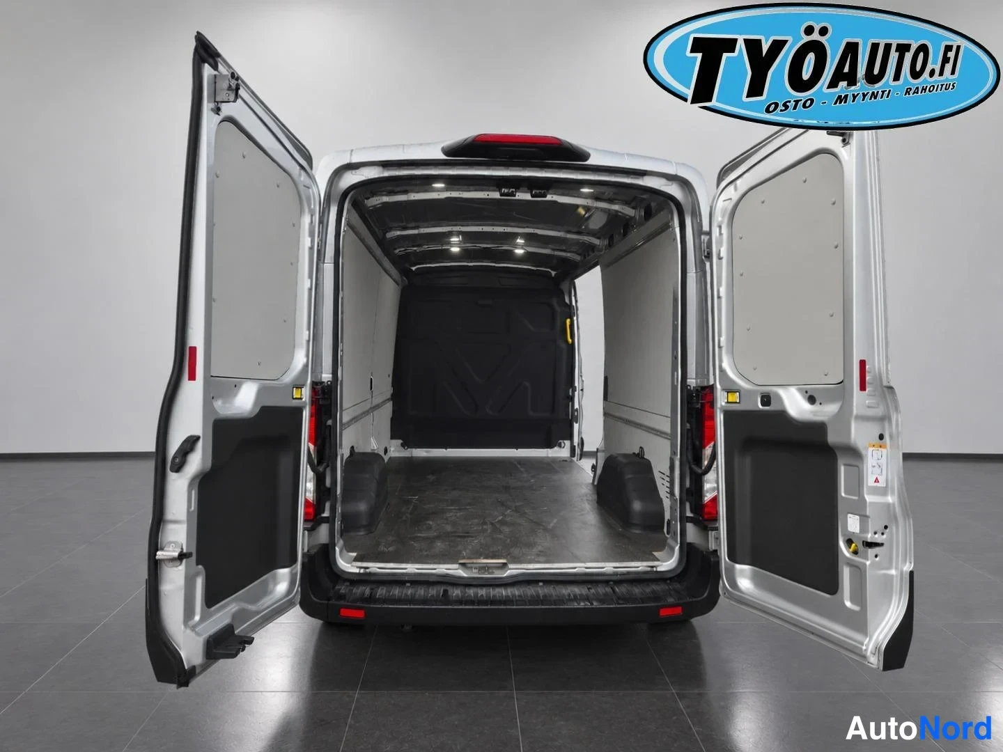 Takaa: Rear view of silver van with both cargo doors open showing dark floor matting, side wall panels and overhead lights.