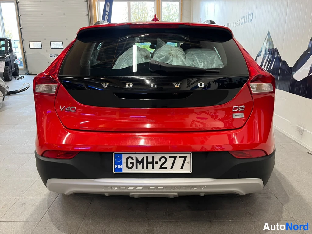 Takaa: Punaisen farmariauton takaosa suoraan takaa; VOLVO-teksti takalasin alla, V40- ja D2-merkit, rekisterikilpi sekä CROSS COUNTRY -teksti alavirtimessä.