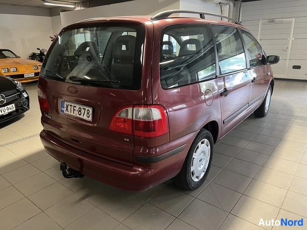 Takaviisto: Punaruskea tila-auto takakolmivartta oikealta, rekisteritunnus, vetokoukku ja kattotelineet näkyvät.