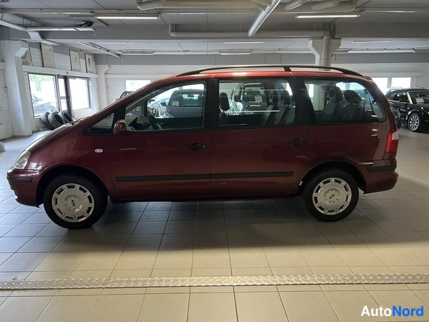 Etuviisto, nokka vasemmalle: Tummanpunainen Ford Galaxy sivusta etukulmasta: vasen kylki ja keulanosa näkyvillä ajohallissa.