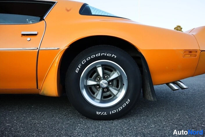 Takaviisto: Oranssin auton takakulma ja takapyörä, BFGoodrich Radial T/A -renkaita ja kaksoispakoputki.
