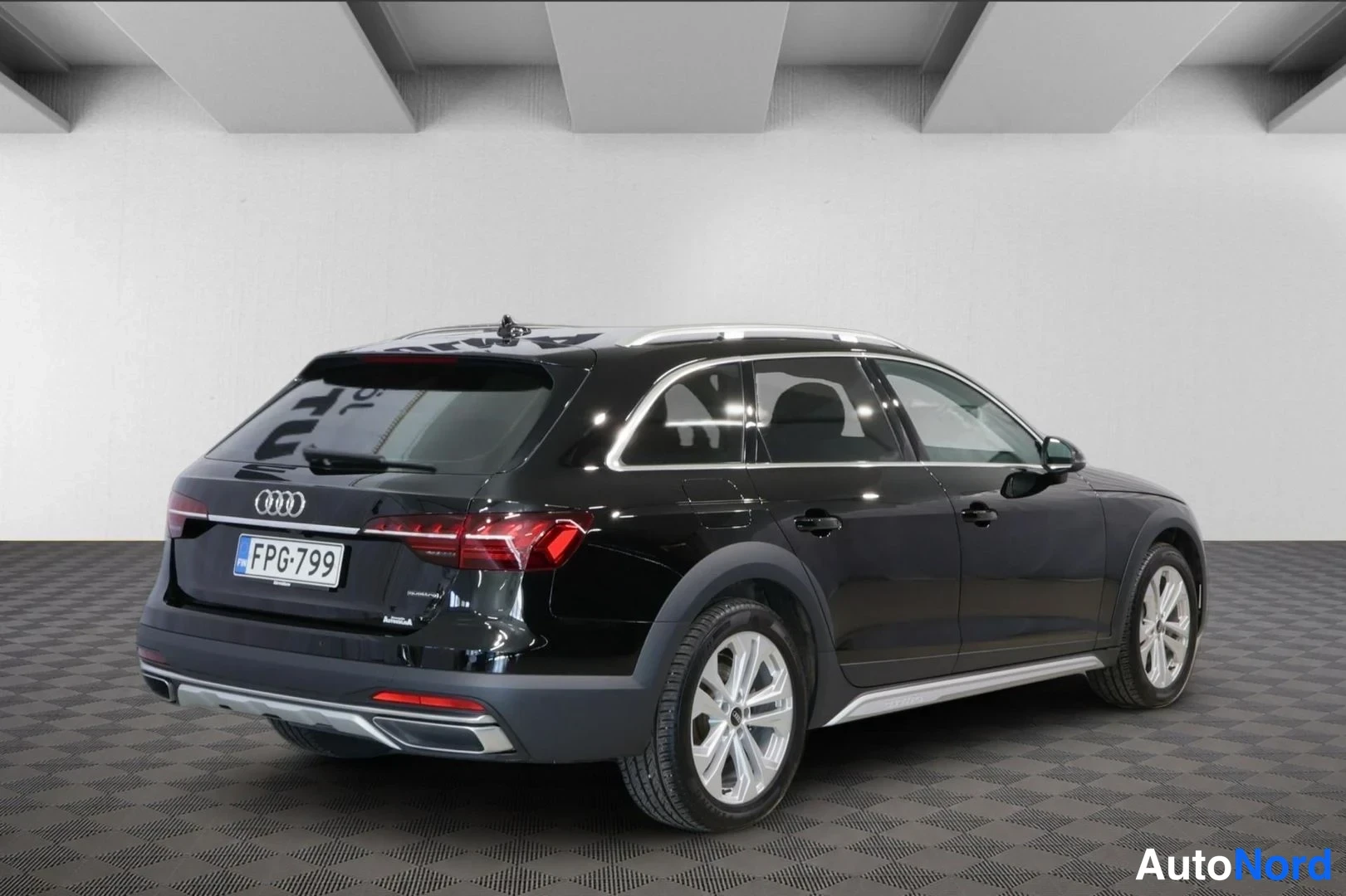 Takaviisto: Musta Audi A4 Allroad takaviistosta oikealta, hopeiset kattokaiteet ja rekisterikilpi näkyvissä.