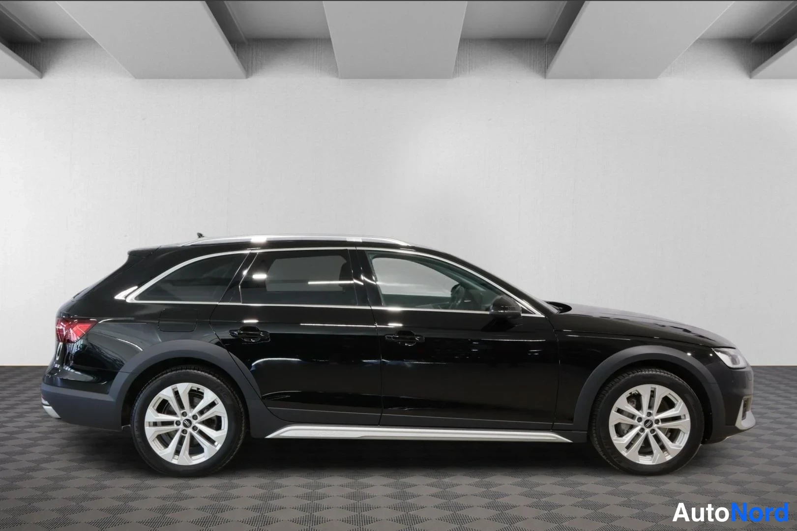 Takaviisto: Musta Audi A4 Allroad vasemmalta sivulta, hopeiset kattokaiteet ja sivukorokkeet, studiovalaistu tila.