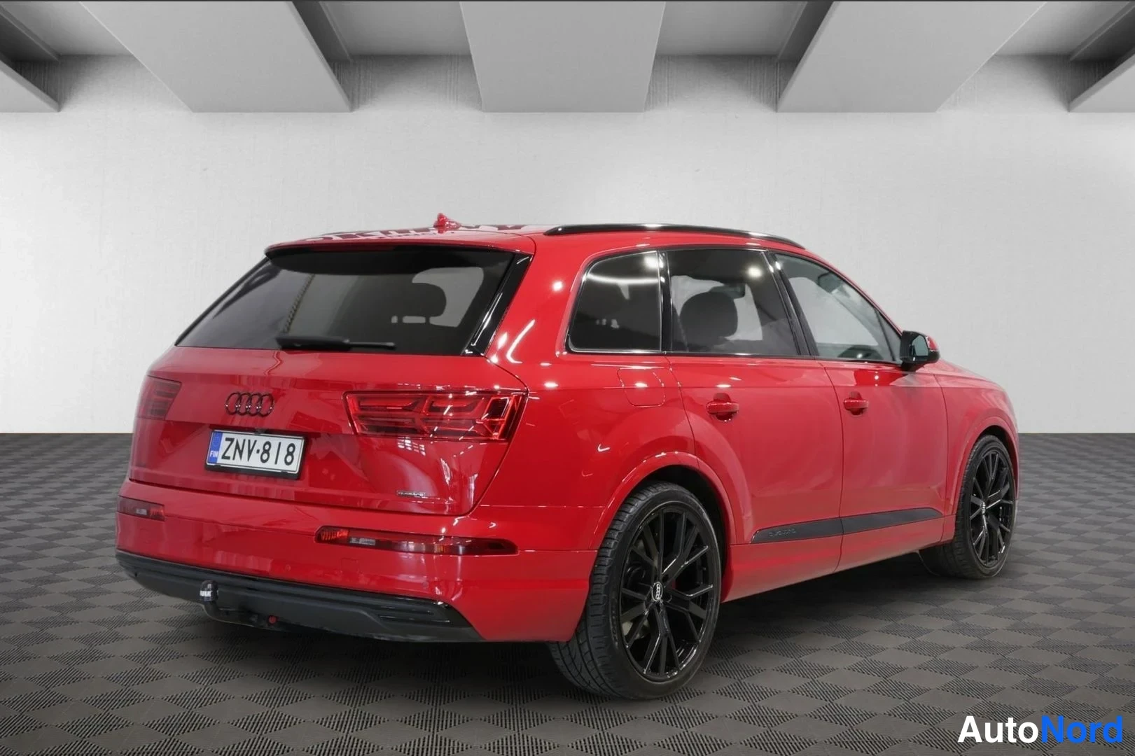 Takaviisto: Audi Q7 tikkupolttoainemittarin takaa takakulmasta, mustat vanteet ja rekisteritunnus.