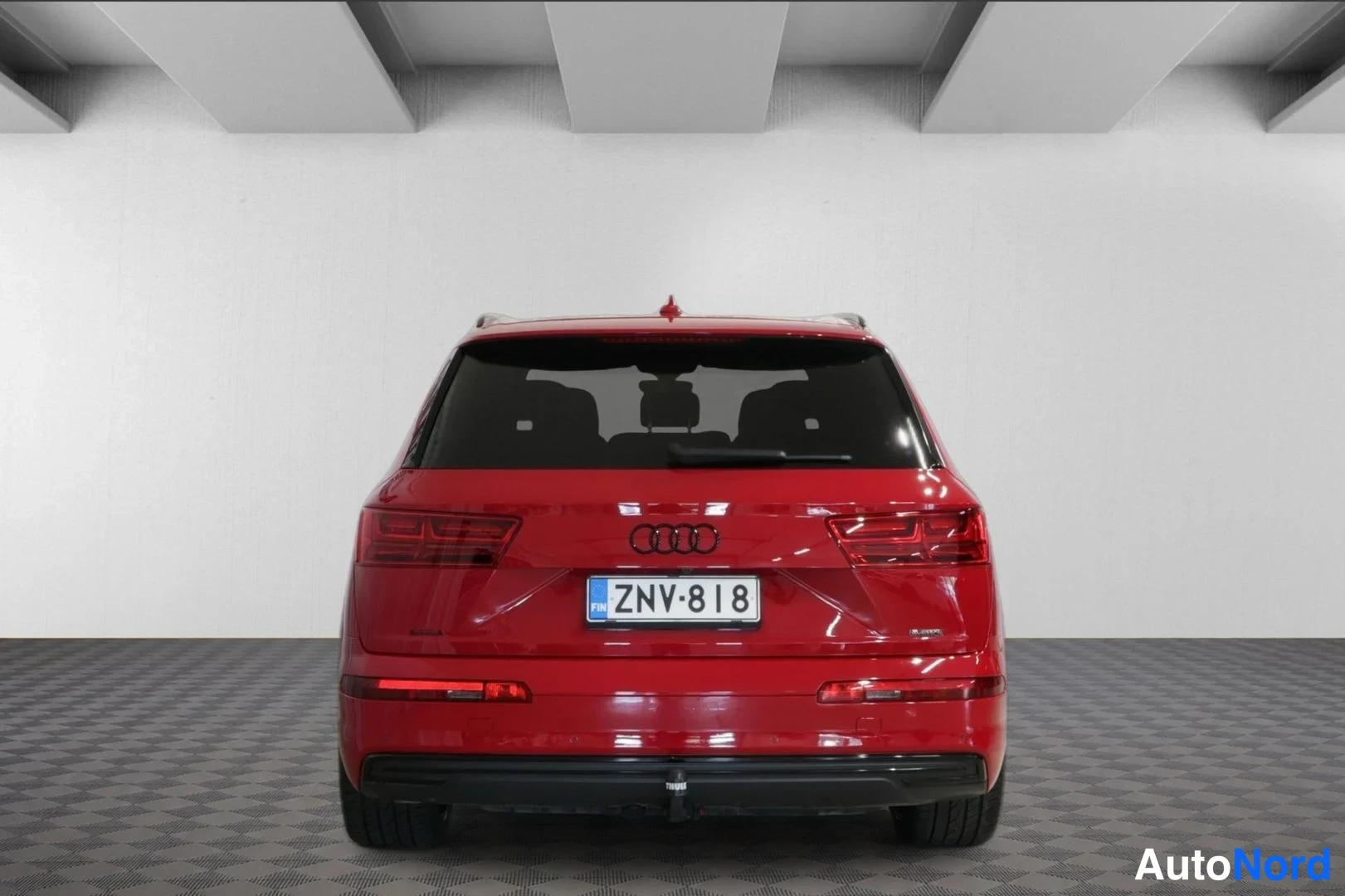 Takaa: Audi Q7:n takaapäin otettu kuva, punainen koriväri, rekisterikilpi, kannessa Audi-merkki ja takavalojen kehykset.