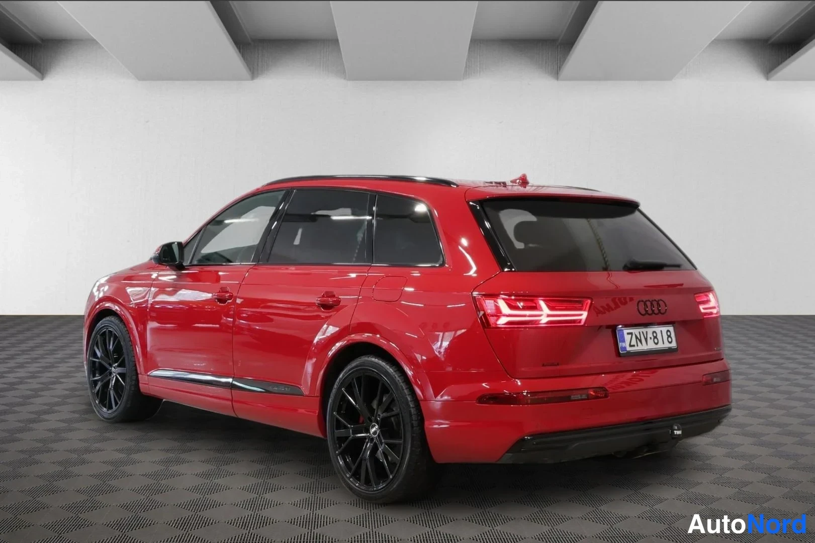 Takaviisto: Audi Q7 takaviisto oikealta, punainen kori, mustat vanteet, rekisterikilpi ja takaosa valaistut takavalot.