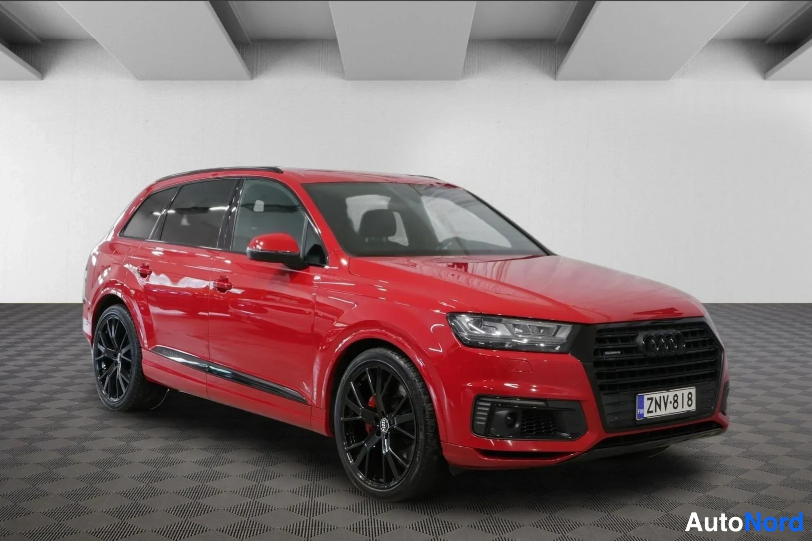 Etuviisto, nokka oikealle: Audi Q7 etuviisto oikealta, punainen kori, musta etusäleikkö ja mustat vanteet, rekisterikilpi.