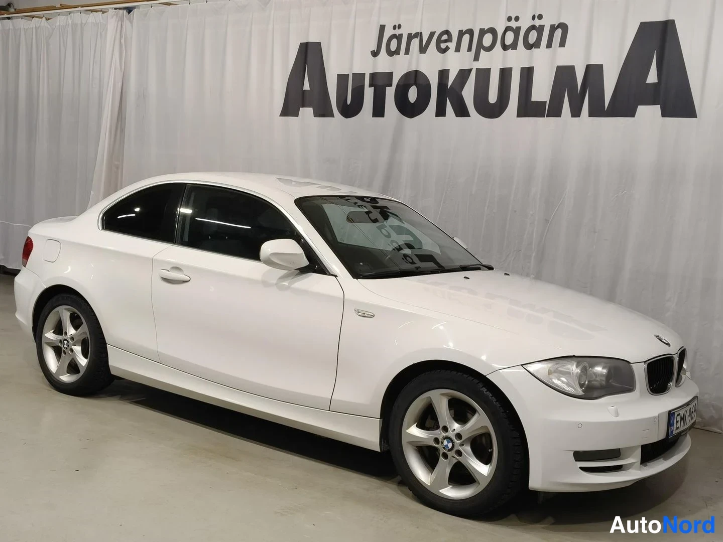 Etuviisto, nokka oikealle: Valkoinen BMW-kupé etukolmasosanäkymässä nokka oikealla, rekisterikilpi näkyvissä.