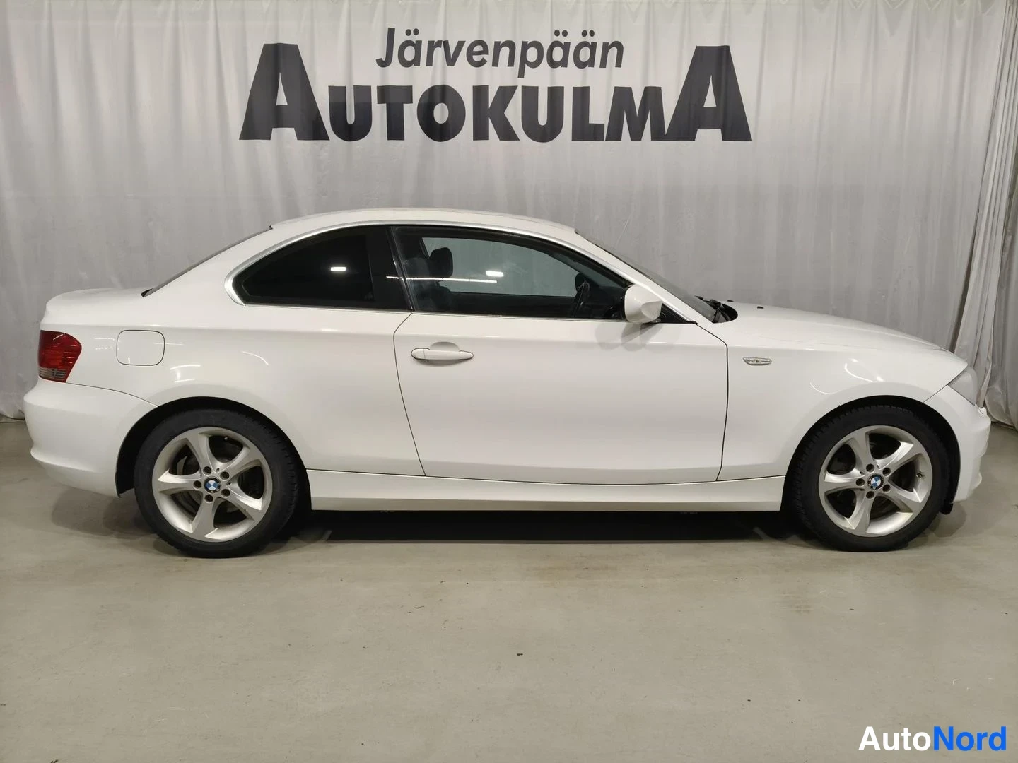 Sivulta: Valkoisen coupé-auton oikea sivuprofiili studiohaulissa, valkoinen verho taustalla.