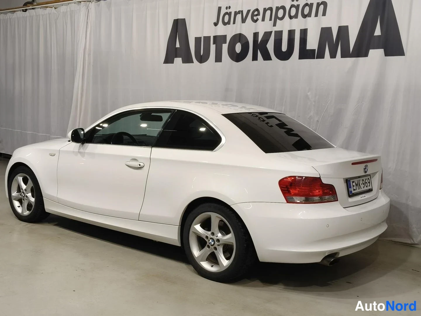 Takaviisto: Valkoisen coupé-auton takaosa ja oikea kylki kolmasosan-kulmassa, rekisterikilpi.