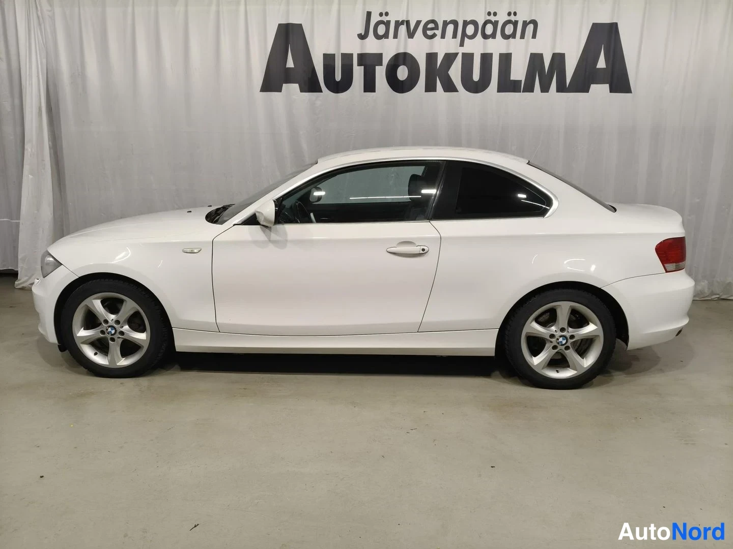 Sivulta: Valkoisen coupé-auton vasen sivuprofiili studiohaulissa.