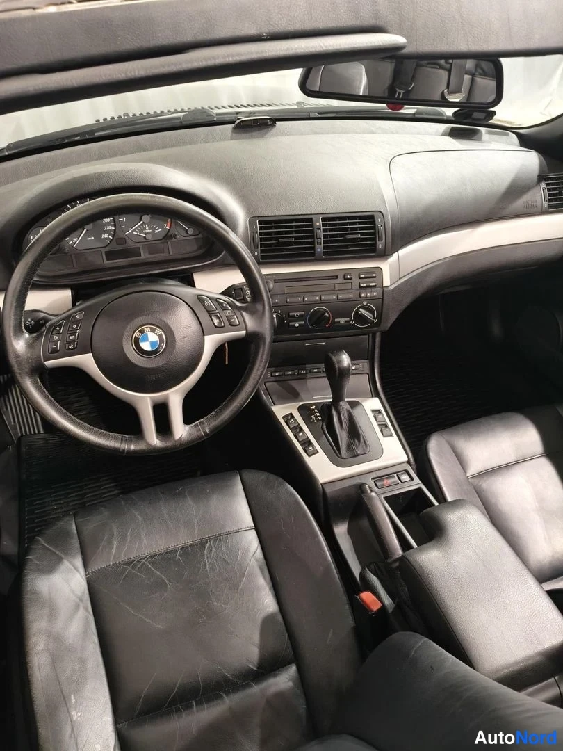 Etuviisto, nokka vasemmalle: BMW:n ohjaamo etuosalta: monitoimiohjauspyörä, mittaristo, automaattivaihteen valitsin ja keskinäylinen konsoli; tumma sisusta.